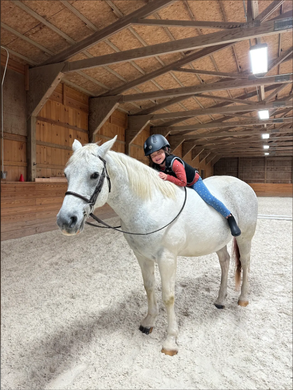 Young camper smiling on a white horse at Furlyn Farm